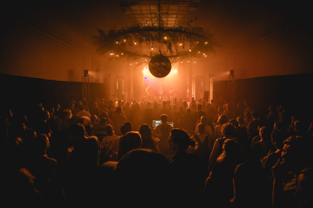 Volle feestzaal met discobal en lichtjes boven een dansend publiek