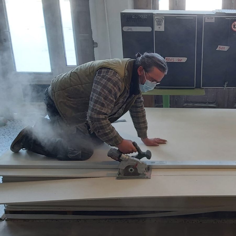 Vrijwilliger van Casinovatief die hout aan het zagen is
