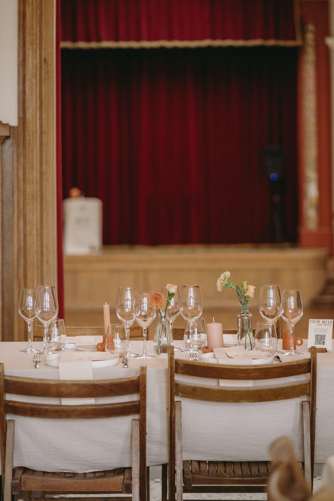 Feestelijk gedekte tafel in de feestzaal voor het podium met rood fluwelen doek
